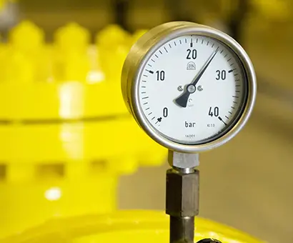 A close up of a pressure gauge on top of a yellow tank.