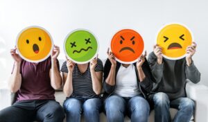 Four people holding up different colored emoticons.