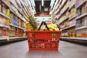 A red basket filled with fruit sitting in the middle of an aisle.